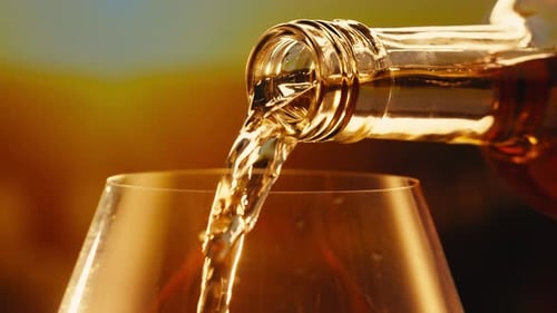 Orange or White Wine Bottle and Glass Against a Sunset in a Peaceful Vineyard Pouring of Ecological