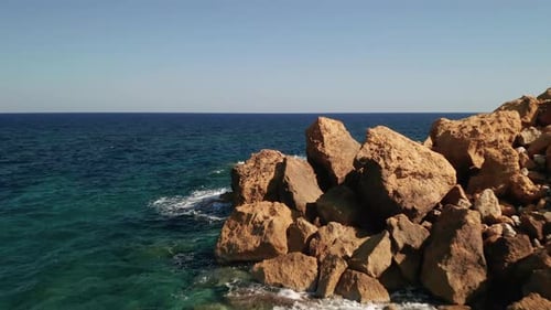Aerial shot of a seashore with beautiful turquoise waters of the Mediterranean Sea splashing on the
