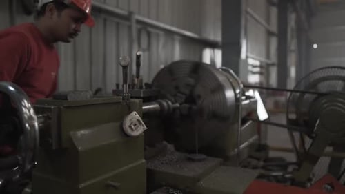 Indischer Fabrikarbeiter programmiert einen CNC-Techniker mit Helm, der in einem mechanischen Hersteller arbeitet