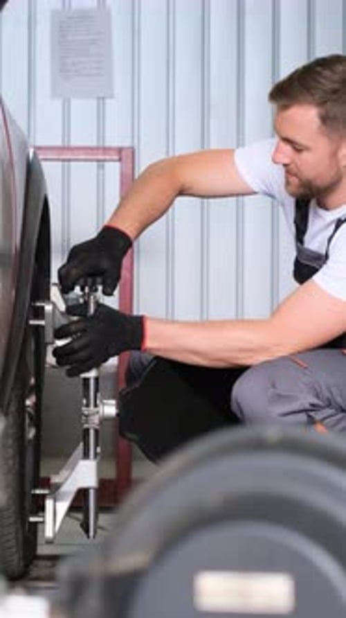 Männlicher Mechaniker repariert Autoräder, Nahaufnahme, vertikales Video