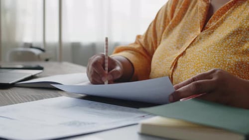 Female Hands Writing in Notebook at Table