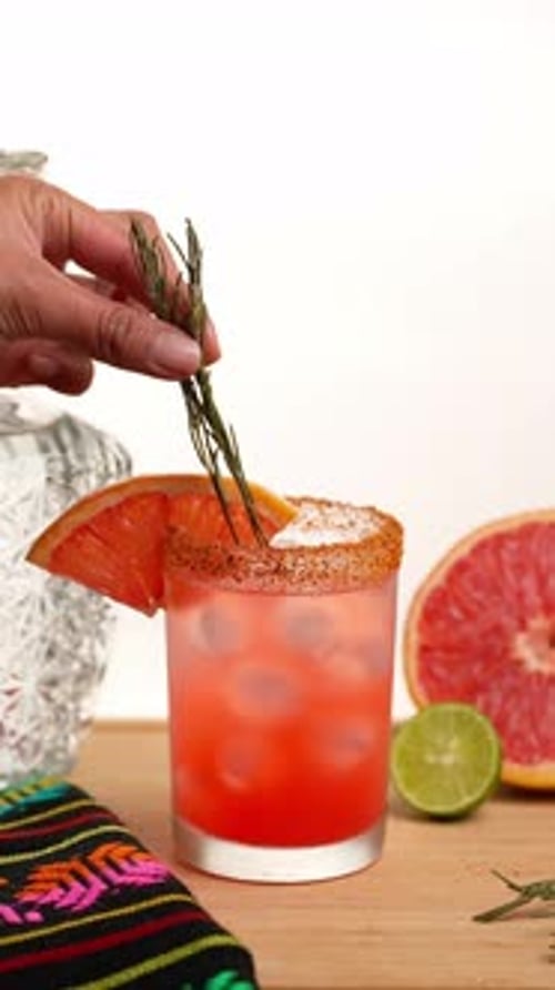 Stylized Refreshment: Woman Garnishing a Grapefruit Cocktail