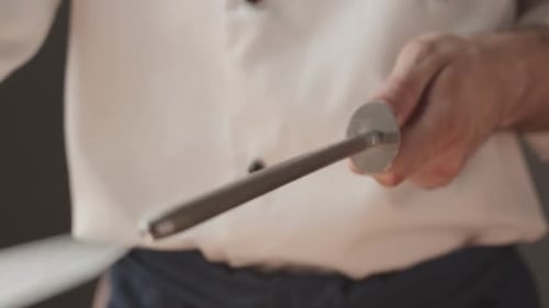 Cook Sharpens Knife on Knife on Domestic Kitchen
