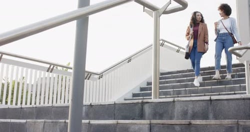 Two Young Women Walking Down Urban Exterior Staircase