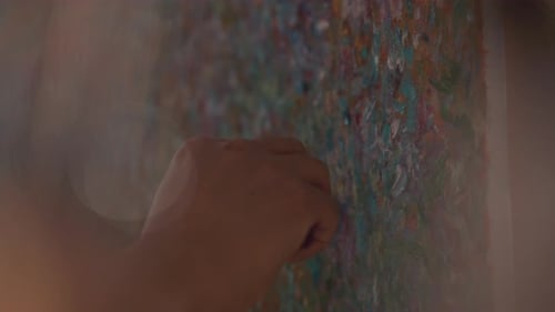 Nahaufnahme eines Künstlers, der mit einem Spachtel dicke Ölfarbe auf die Leinwand aufträgt