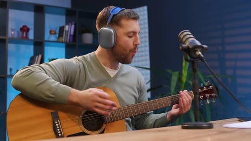 Songwriter with acoustic guitar. Man with microphone in the studio, conception of podcast.