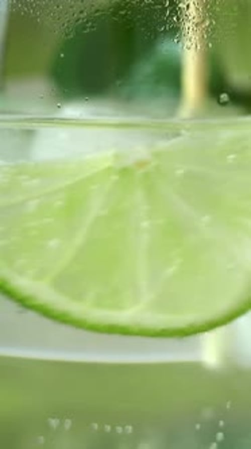 Close Up Mojito Cocktail in Glass with Lime Mint and Ice is Stirred with Spoon