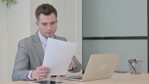 Adult Man Reading Document at Modern Office Desk