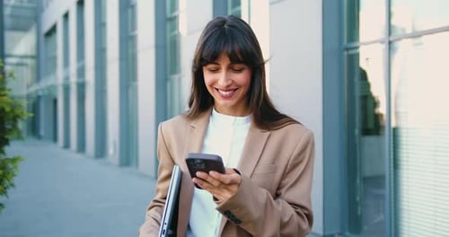 Portrait of Young Caucasian Woman Holding a Smartphone and Reacting with Surprise to Unexpected News