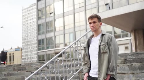 A young handsome man in a green shirt strolls through the center of town.