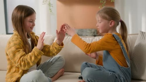 Two Young Girls Playing Hand Clapping Game Indoors