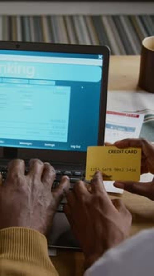 African American Man using Banking Website and Holding Credit Card Vertical