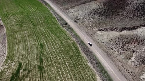 Luftbild des Autos auf einer unbefestigten Straße zwischen Feldern 4K