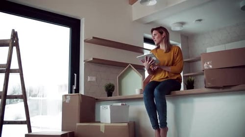 Woman Using Tablet in New Home with Boxes