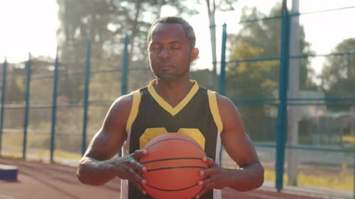 Man Holding Basketball on Outdoor Court
