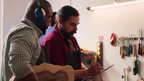 Craftsmen Inspect Wood Panel in Bright Workshop