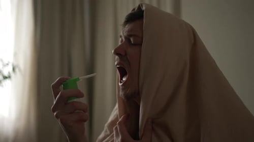 Sick Man Using Nasal Spray at Home