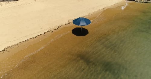 Aerial drone orbiting rotating shot of lonely sun umbrella in the sand of a beautiful desert beach i