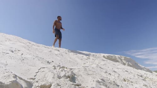Der sexy schwarze Tausendjährige schaut von der Spitze der Sanddüne auf den Strand