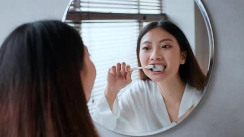 Woman Brushing Teeth in Bathroom Mirror, Oral Hygiene