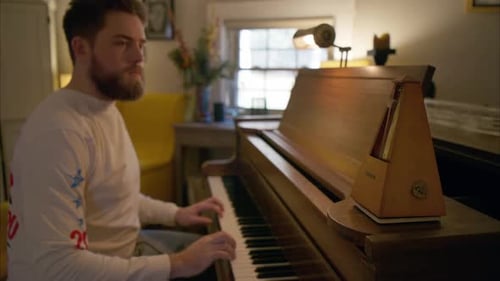 Man Plays Piano with Metronome in Home