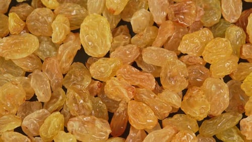 Green raisins slowly rotating in macro background. Dried fruits and dry berries. Dried grapes