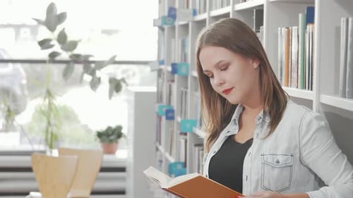 Charming Young Woman Joyfully Reading a Book in a Cozy Library