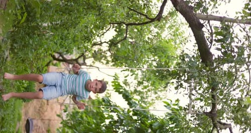 Happy Little Boy Swinging on a Swing in the Garden
