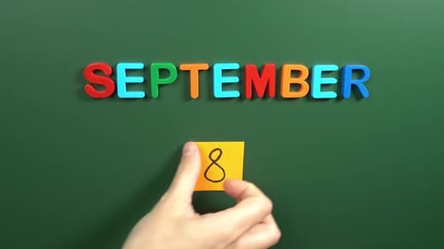 Hand sticking a sticker 8 September calendar day on school board. 8 date of September. Eighth day