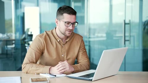 Businessman talking at a business meeting on a video call using a laptop computer while sitting