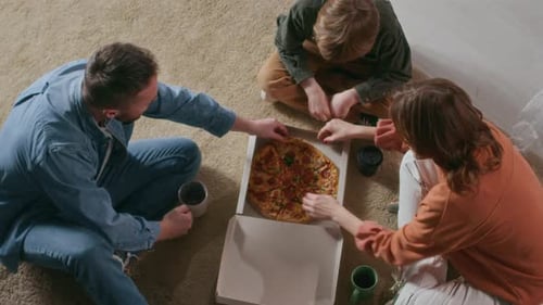 Family Sharing Pizza on the Floor at Home