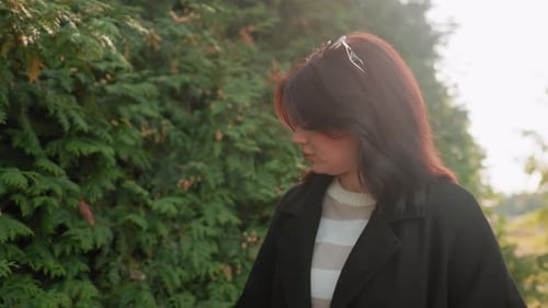 Lady Walking Touching Autumn Foliage Beside Green Hedge