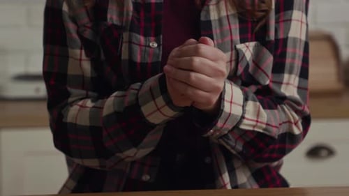 Une jeune femme vêtue d'une chemise à carreaux est capturée dans une photo détaillée en train de se frotter les mains