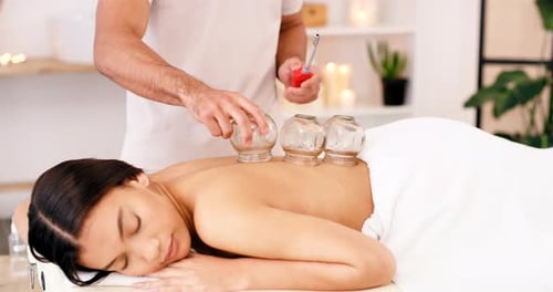 Woman, spa and cupping therapy on patient back, therapist putting cups on skin for pain