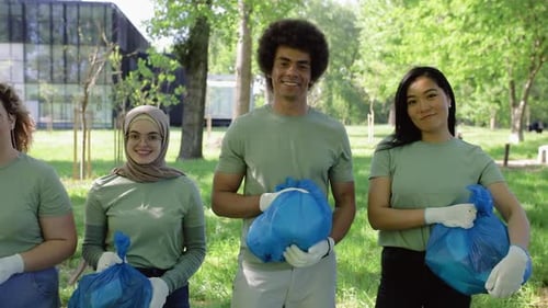 Portrait of multiethnic group of volunteers with garbage bags after cleaning city park.