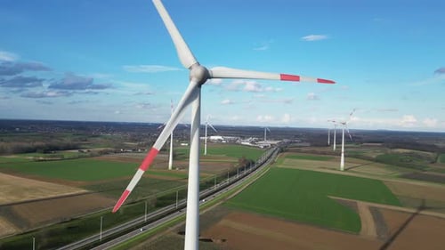 Wind turbines next to highway provide electricity for charging electric vehicles