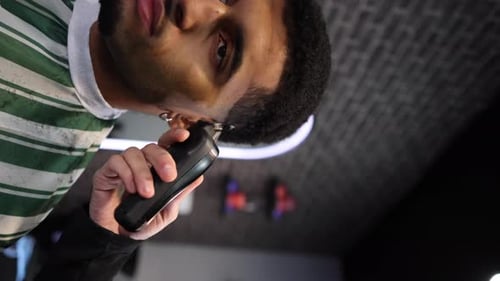 Eine Nahaufnahme eines Friseurs, der in einem Friseurladen vorsichtig die Haare eines Mannes mit einer Haarschneidemaschine schneidet.