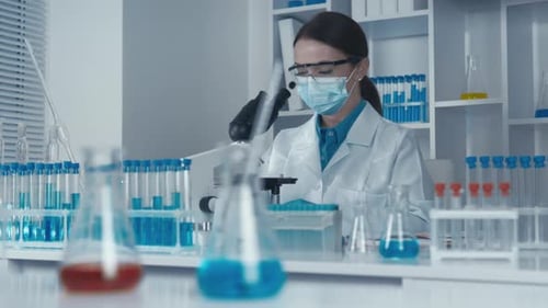 Scientist Works With Microscope in Brightly Lit Lab