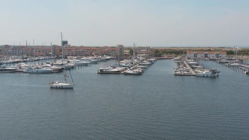 Drone cinématographique/panorama aérien d'un port de plaisance avec des voiliers, un bateau naviguant dans le premier