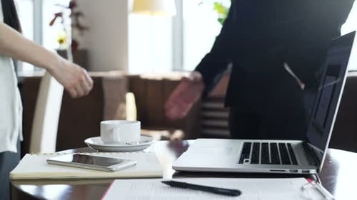 Business handshake in modern office, coffee and laptop