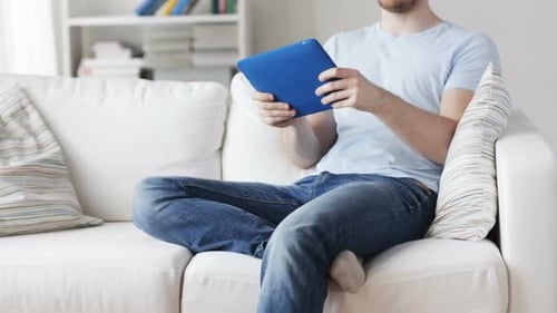 Man Using Tablet Sitting on a White Couch