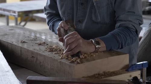 Man Using Hand Plane on Wood in Workshop