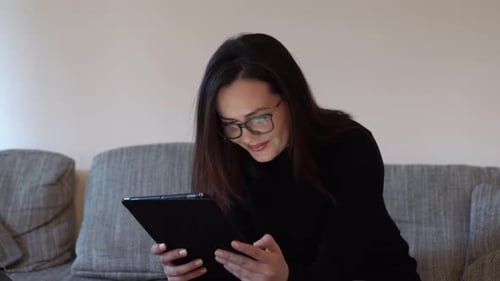 Woman Using Tablet Device Sitting on Couch