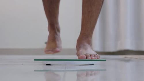 Hombre que analiza el peso mientras está de pie en una báscula