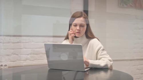 Woman working on laptop at home answers phone