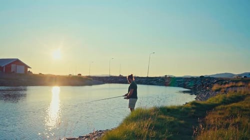 Lake Illuminated Sunset Light With Man Fishing In Kokelv, Norway. Wide Shot
