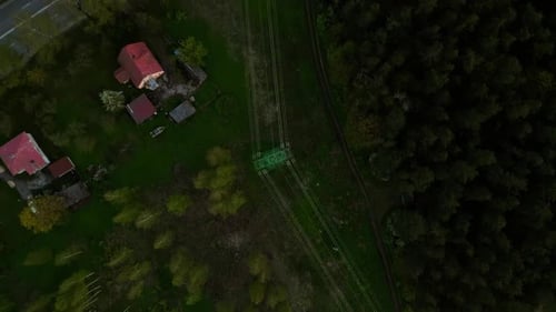 Aerial View of Homes in the Countryside Surrounded By Lush Forest with Railway Tracks Weaving