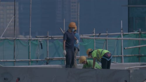 Builders On The Roof Of A High Rise Building Under Construction In Hong Kong