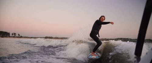 Man Wake Surfing on Lake at Sunrise