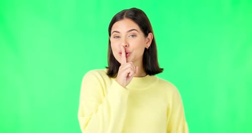 Green screen, happy face and secret woman with finger on lips, wink and privacy in studio